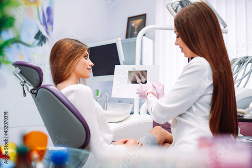 Young woman at the dentist's chair during a dental procedure. Dentist examining patient's teeth in modern clinic. Healthy teeth and medicine concept.
