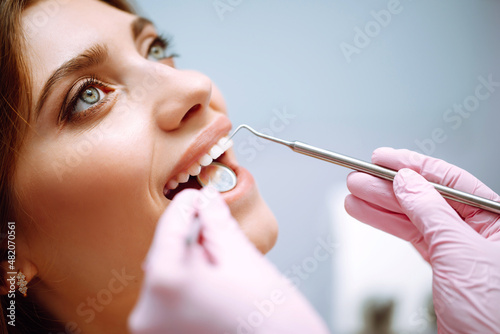 Young woman at the dentist's chair during a dental procedure. Dentist examining patient's teeth in modern clinic. Healthy teeth and medicine concept.