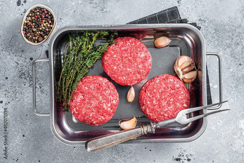 Fresh Raw Ground mince beef meat Hamburger steak patty in a steel tray. Gray background. Top view