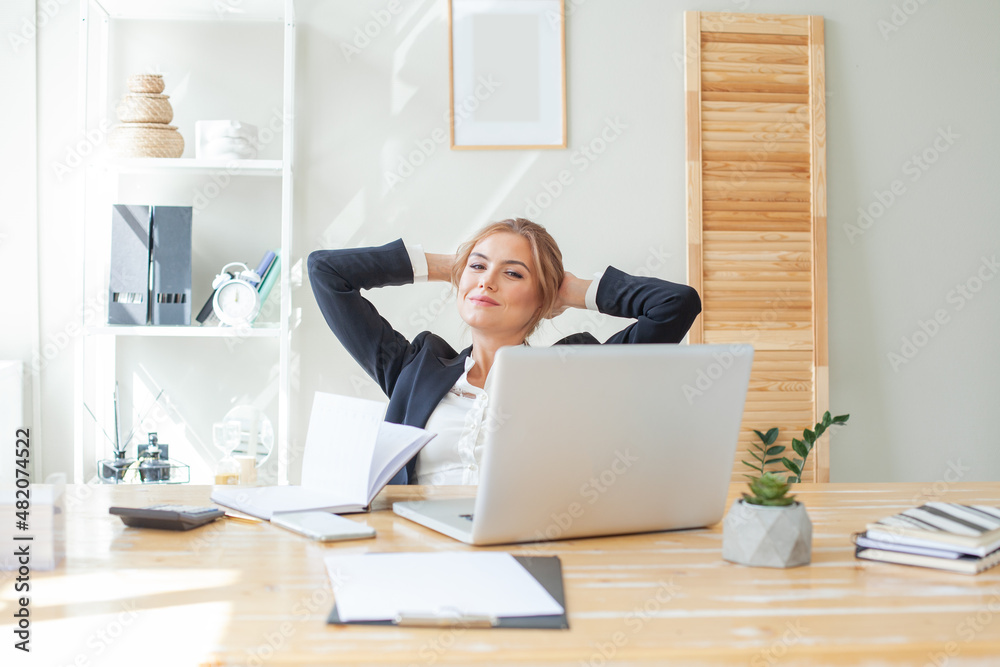 Happy businesswoman resting and smiling while sitting at desk in office