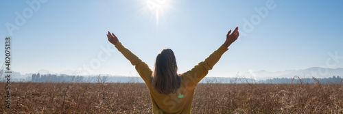Canvas Print Young woman standing in a field with spread arms