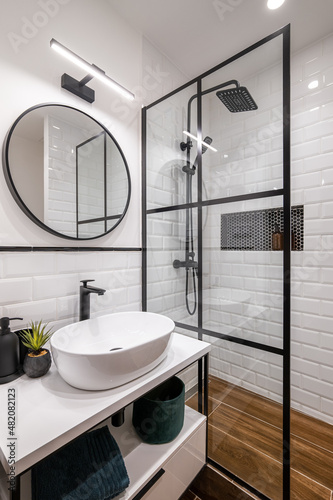 Simple bathroom with black shower  round mirror and classic white tiles