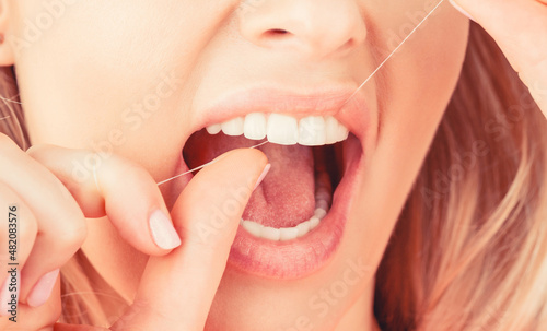 Dental floss. Taking care of teeth. Healthy teeth concept. Teeth Flossing. Oral hygiene and health care. Smiling women use dental floss white healthy teeth. Dental flush - woman flossing teeth