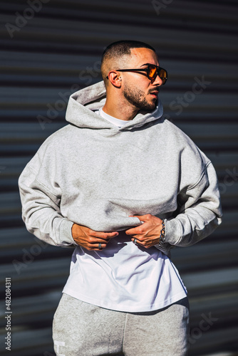 hombre con gafas de sol poniéndose una sudadera gris