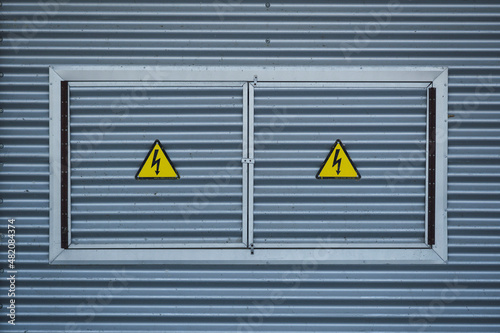 sign on a wall, high voltage singal, yellow sign with a lightning
 photo