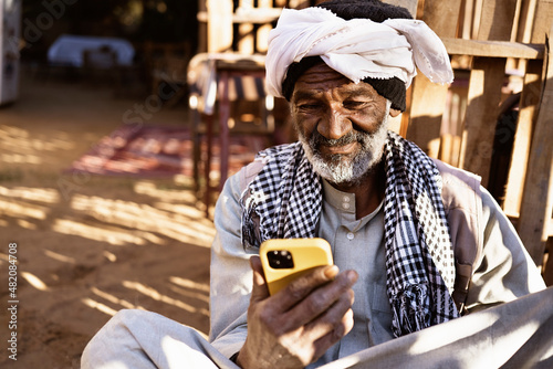 Senior ethnic man with smartphone on street