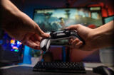 A gamer with a gamepad in his hands plays a video game on a large TV screen. Online games with friends, winnings, prizes. Adventure and sports games. Neon lighting.