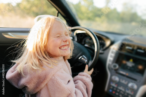 Happy girl sitting on driver seat