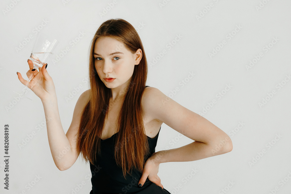 Dressed up young woman posing, holding a water glass, looking at the camera Dressed up young woman posing, holding a water glass, looking at the camera