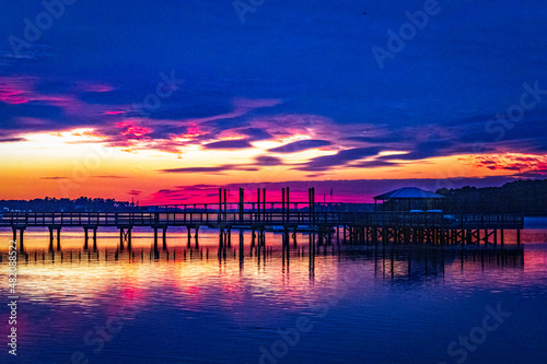 A colorful blue hour sunset of a pier with a bridge in the background off of Hilton Head Island with a nice reflection in the water.