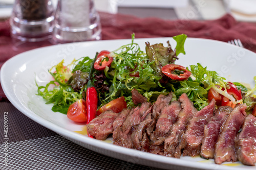 Steak salad with beef and vegetables on a white plate