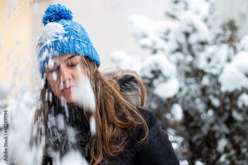 Pretty girl with long hair in a fur coat in winter standing under falling snow