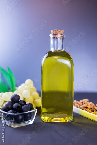 olive oil in a glass bottle with black olives and grapes