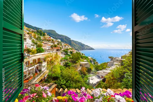 Naklejka na ścianę Mountain, city and sea view through an open window with shutters of the city of Positano on the Amalfi Coast of Southern Italy during summer.