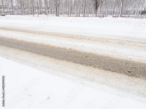 Snowdrifts on the side of the road. Bad weather and traffic. Snow on asphalt. Difficult driving conditions. Winter slosh on the road. Braking distance of a car.