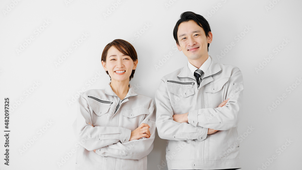 白壁を背にして立つ作業服のビジネスマンとビジネスウーマン 白壁を背にして立つ作業服のビジネスマンとビジネスウーマン