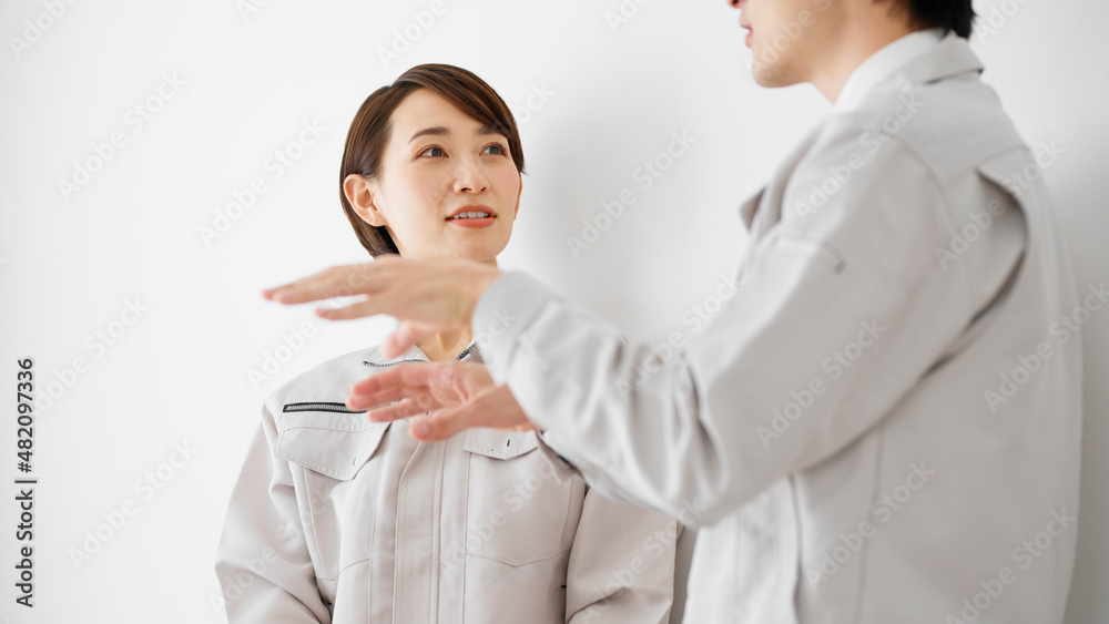 白壁を背にして立つ作業服のビジネスマンとビジネスウーマン 白壁を背にして立つ作業服のビジネスマンとビジネスウーマン
