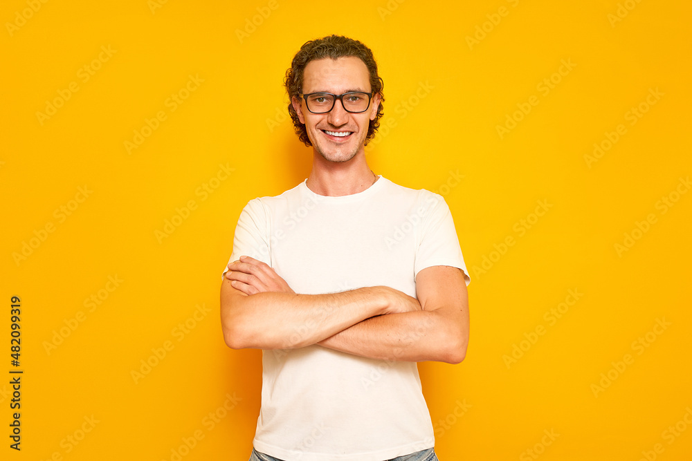 Obraz premium confident man with smiling teeth, glasses is dressed in casual clothes crossed his arms on his chest, looks in front of him. isolated on yellow studio background with space for text. concept - people