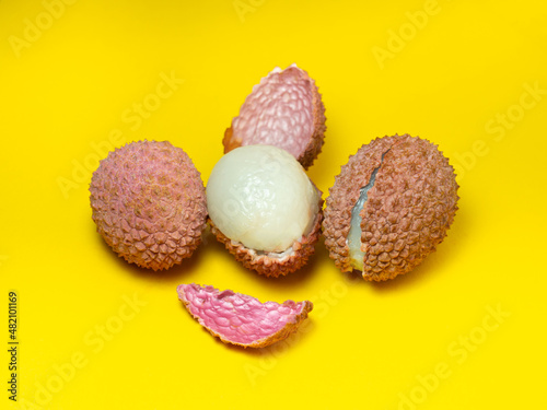 Sliced ​​lychee. Round pimply fruits. Chinese plum. Fruit peel. Peeling the lychee. Pieces of juicy fruit on a bright background.