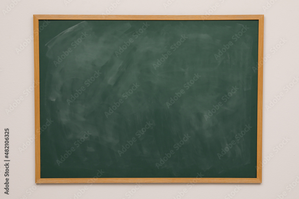 Clean green chalkboard hanging on grey wall Clean green chalkboard hanging on grey wall