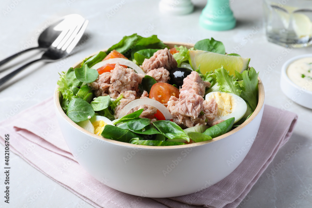 Bowl of delicious salad with canned tuna and vegetables on light table Bowl of delicious salad with canned tuna and vegetables on light table