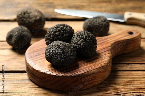 Black truffles with board on wooden table