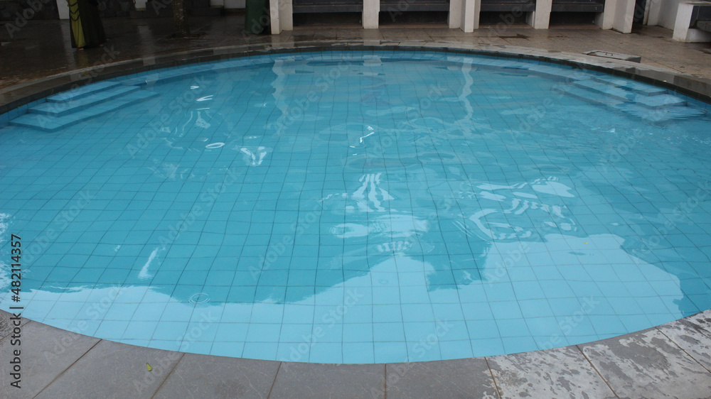 an oval-shaped swimming pool with water that is so clear and clean and the ground floor of the pool is sea blue