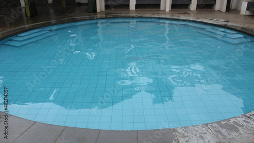an oval-shaped swimming pool with water that is so clear and clean and the ground floor of the pool is sea blue © Duy666
