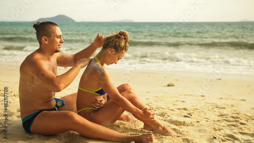 Carefree barefoot loving couple having sun block. Woman to put s