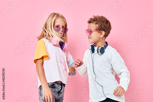 cute smiling kids entertainment headphones playing pink color background