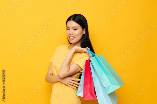 pretty brunette in a yellow T-shirt with multicolored shopping bags studio model unaltered