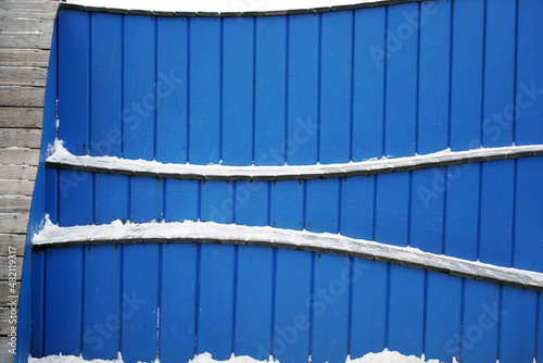 Wavy-shaped benches made of blue wood are covered with snow photo