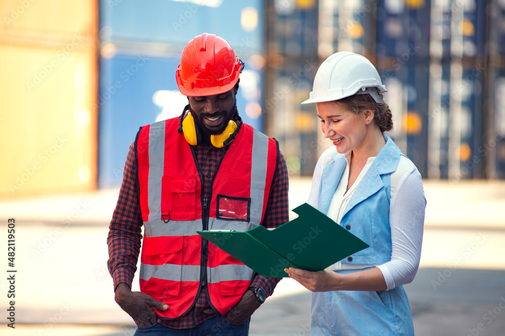 Fototapeta premium Businesswoman and engineer talking and checking loading Containers box from Cargo freight ship for import export. shipping in docks.