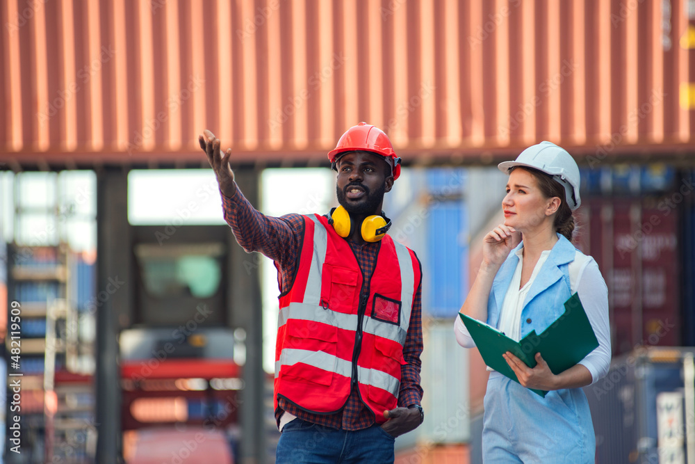 Obraz premium Businesswoman and engineer talking and checking loading Containers box from Cargo freight ship for import export. shipping in docks.