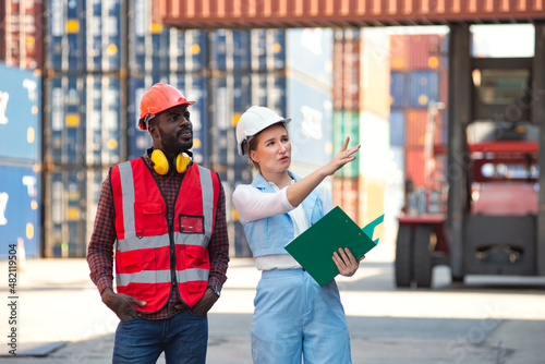 Businesswoman and engineer talking and checking loading Containers box from Cargo freight ship for import export. shipping in docks. © Thanumporn