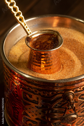 Foto Traditional Turkish coffee with foam in cezve prepared on hot sand in authentic Turkish Copper