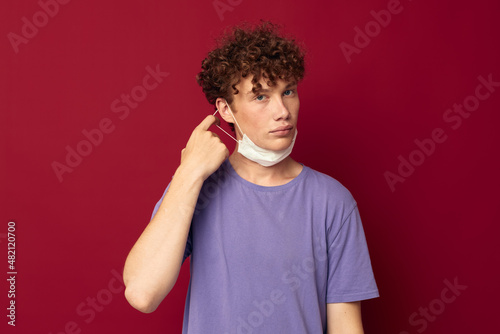 A young man medical mask protection posing red background unaltered