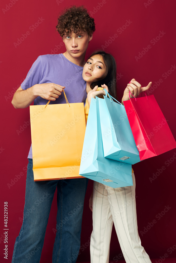 cute young couple in colorful T-shirts with bags Shopping red background unaltered cute young couple in colorful T-shirts with bags Shopping red background unaltered