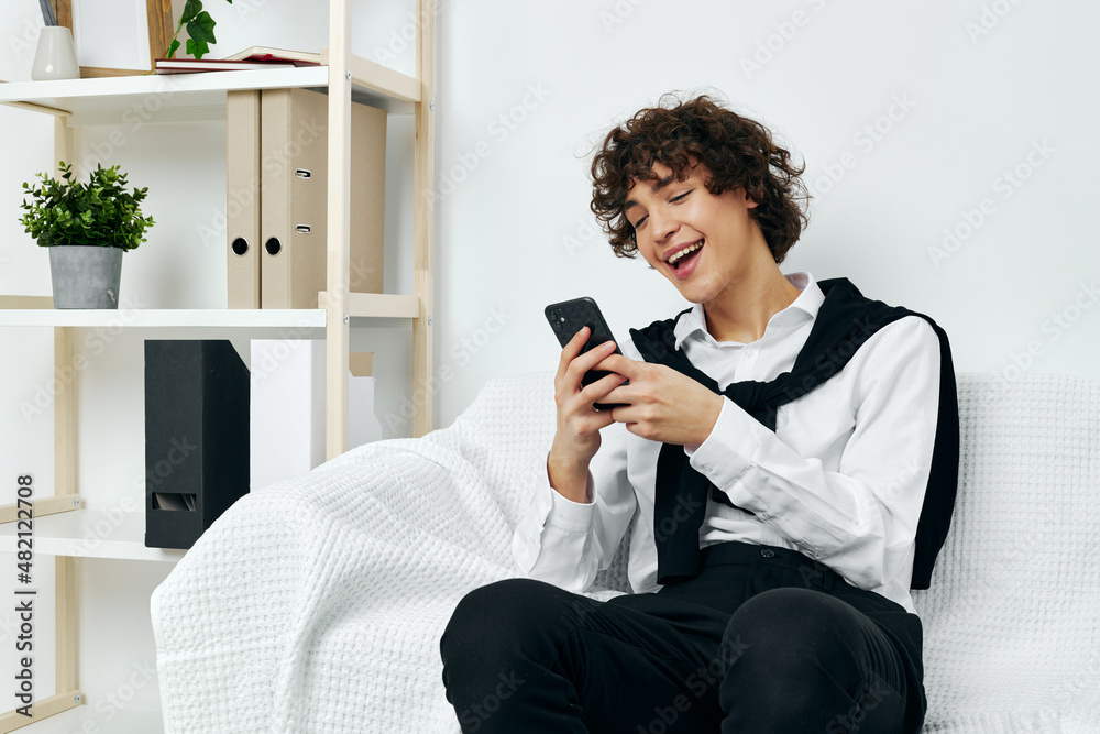 curly guy sitting on a white sofa smartphone Lifestyle technology curly guy sitting on a white sofa smartphone Lifestyle technology