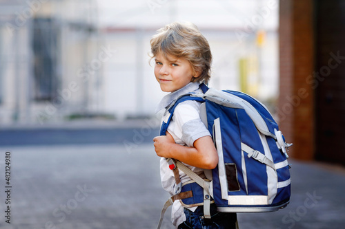 Happy little kid boy with backpack or satchel called Ranzen in German. Schoolkid on way to school. Portrait of healthy adorable child outdoors. Student  pupil  back to school. Elementary school age