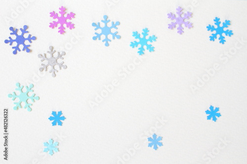 Colored snowflake paper crafts on white textured paper background for wall paper. Blank for copy space.