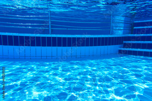 Underwater part of the pool with tiles and reflections on the bottom