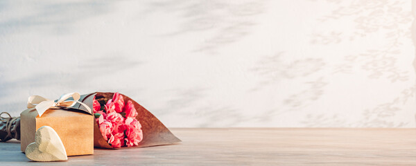 Wooden heart, gift and flowers on the table as a background for Mother's Day