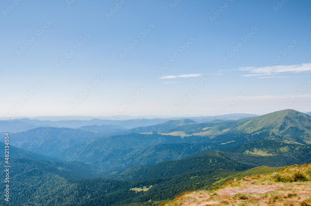summer landscape, green peaks of mountain hills against the background of the morning blue sky. High quality photo