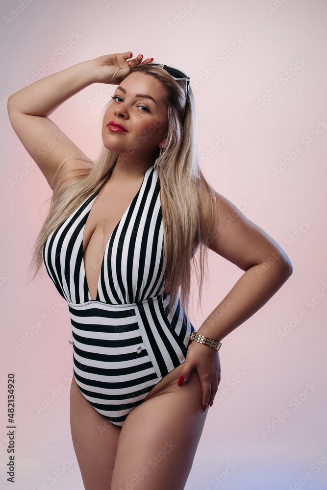 stylish female model with long hair in black and white swimsuit touching her sunglasses and posing to the camera stylish female model with long hair in black and white swimsuit touching her sunglasses and posing to the camera