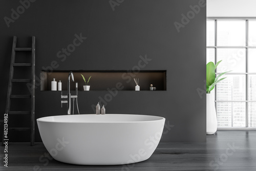 Modern bathroom interior with white ceramic bathtub. Dark gray walls and hardwood flooring. Panoramic window. Ladder. No people. 3d rendering.