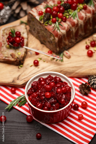 Cranberry sauce with Traditional French terrine on dark wooden background with Christmas decorations