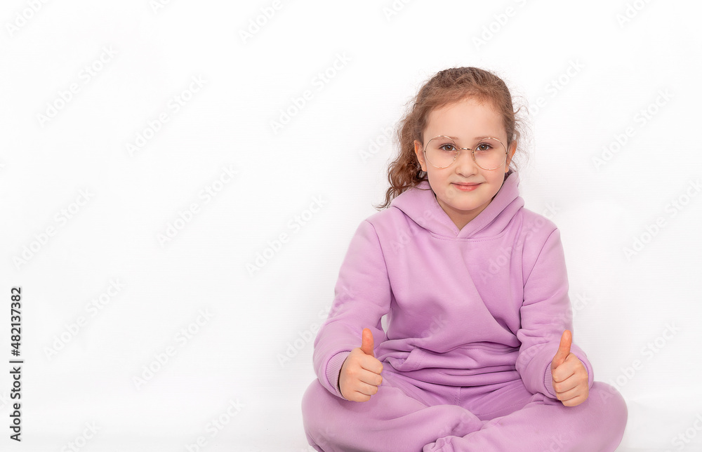 Cute cheerful positive little girl in glasses and hoodie, showing two thumbs up. Isolated on a white background Cute cheerful positive little girl in glasses and hoodie, showing two thumbs up. Isolated on a white background