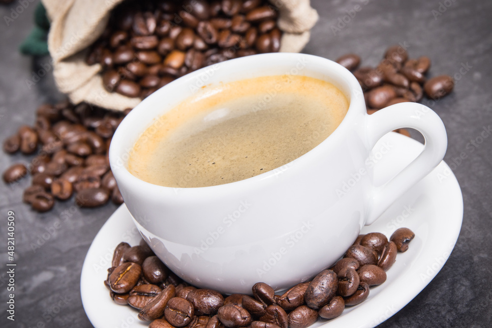 Coffee in white cup and roasted dark coffee beans in bag Coffee in white cup and roasted dark coffee beans in bag