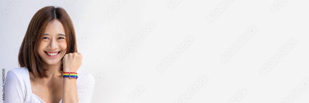 Confident asian LGBT woman wearing LGBTQ rainbow wristband, concept of gay pride month, lesbian pride, LGBT awareness movement, non-binary inclusivity and diversity Confident asian LGBT woman wearing LGBTQ rainbow wristband, concept of gay pride month, lesbian pride, LGBT awareness movement, non-binary inclusivity and diversity